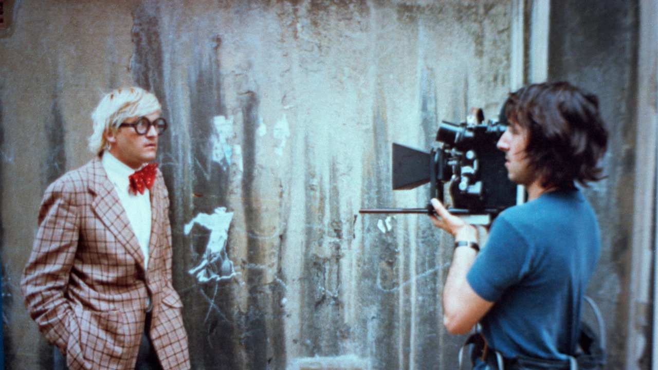 Hockney being filmed in a plaid blazer
